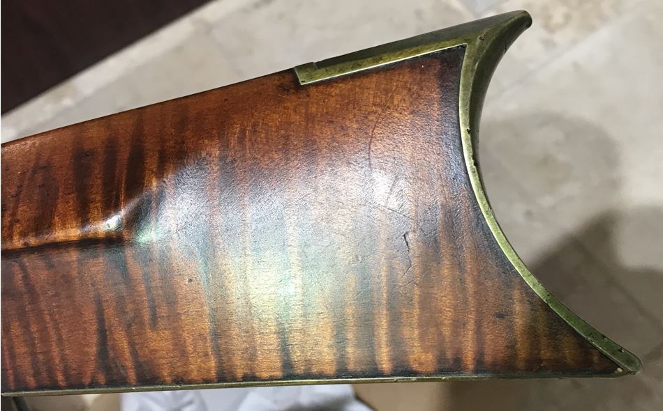 A closeup view of the left-hand side of the buttstock, highlighting the curly grain of the wood.