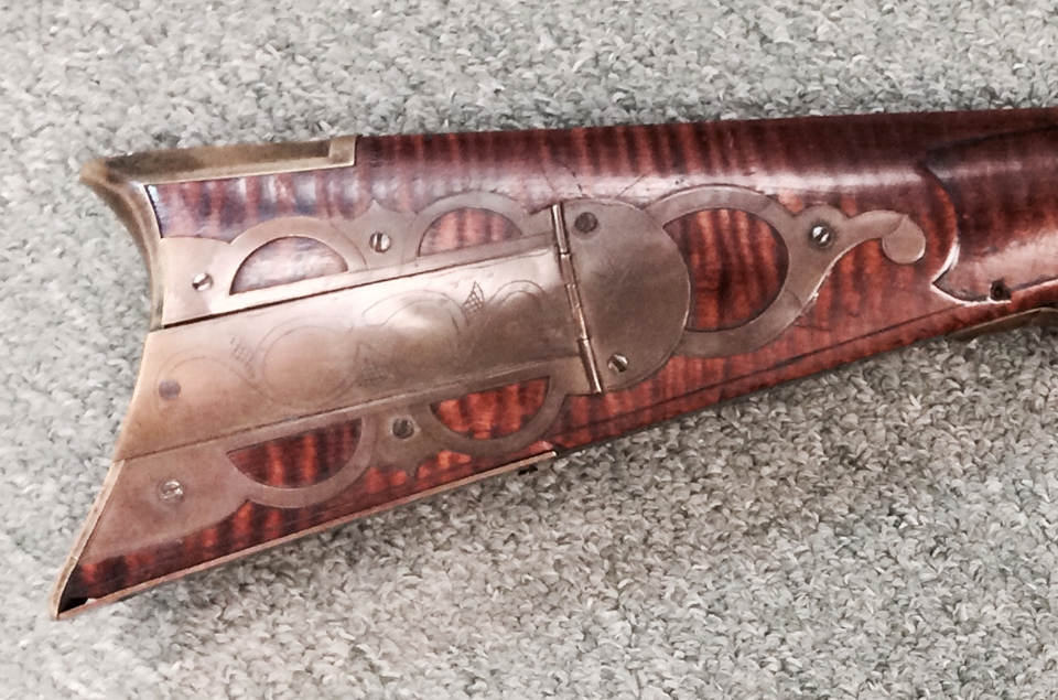 This shows the patch box area on a rifle that was made by Bedford County, Pennsylvania gunsmith Jacob Stoudenour. The patch box has five piercings and a Q-shaped finial.