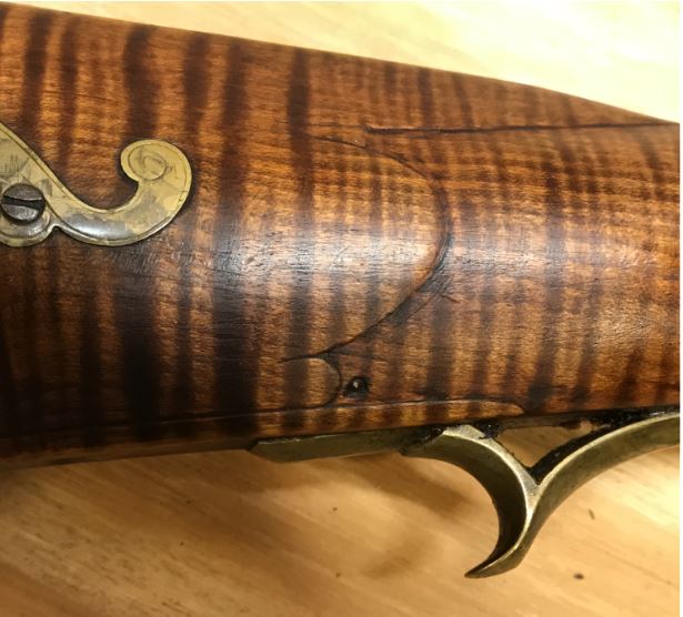  a photo featuring the carving on the right hand side of the wrist of the Mills rifle.