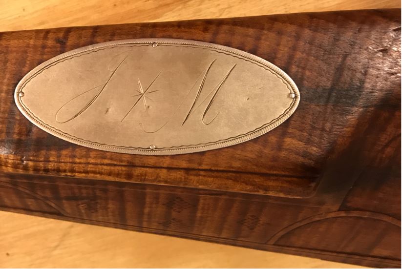 This is a closeup photo of the initialed cheekpiece inlay on the Joseph Mills smooth rifle.