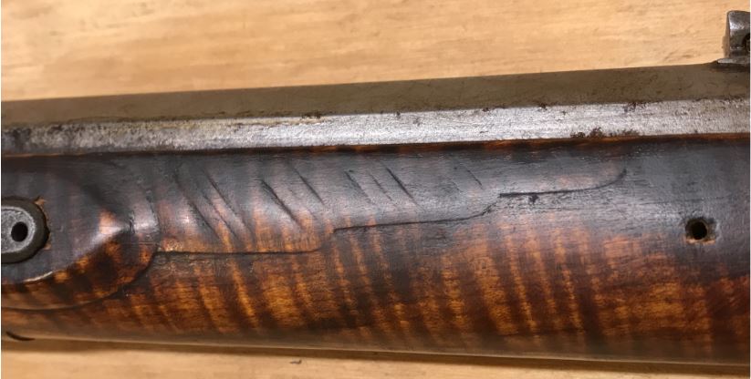 This shows the relief carved 'wing' in front of the lock panel of the antique smooth rifle that was built by Joseph Mills.