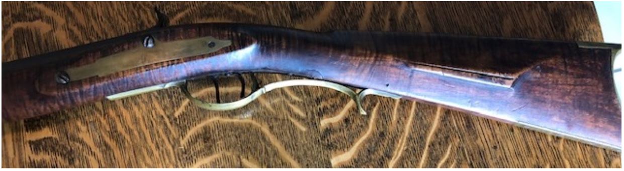 This shows a portion of the left-hand side of a Lepley rifle, including the butt stock, trigger guard area, and lock bolt plate panel area. This muzzle loading black powder rifle was made in Somerset County, Pennsylvania.