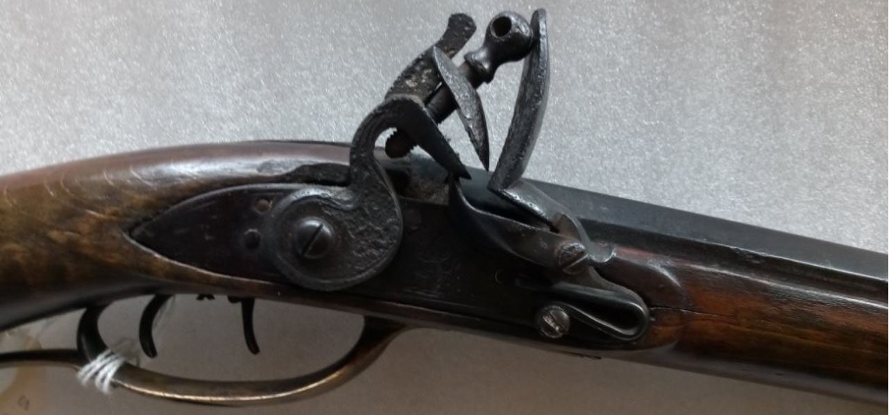 The lock and the mating lock panel of the stock on the antique black powder rifle.